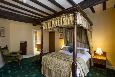a bedroom with a canopy bed and a chair at Prince Rupert Hotel in Shrewsbury