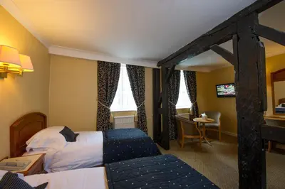 a hotel room with two beds and a table at Prince Rupert Hotel in Shrewsbury