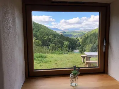 a window with a view of a field and a bench at Glyn Mawr Barn in Bala