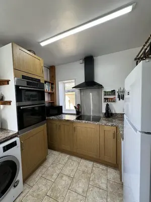 a kitchen with wooden cabinets and a stove top oven at The Moorings in Fairbourne