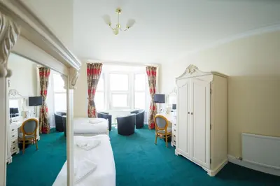 a bedroom with two beds and a table and chairs at Queensbridge Hotel in Aberystwyth