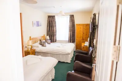 a bedroom with two beds and a chair in it at Queensbridge Hotel in Aberystwyth