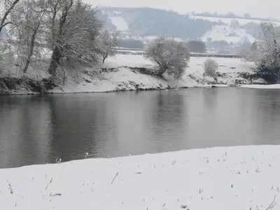 a river covered in snow with trees and a field at Glanwye in Hay-on-Wye