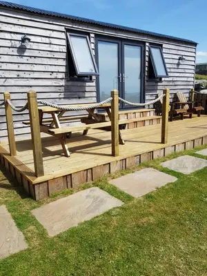 a wooden deck in front of a log cabin at Allibella Shepherds Hut, Amazing Seaview, Private garden, Pet Friendly in Barmouth