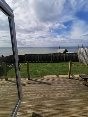 a view of the ocean from a glass door at Allibella Shepherds Hut, Amazing Seaview, Private garden, Pet Friendly in Barmouth