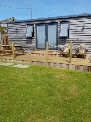 a house with two chairs on a wooden deck at Allibella Shepherds Hut, Amazing Seaview, Private garden, Pet Friendly in Barmouth