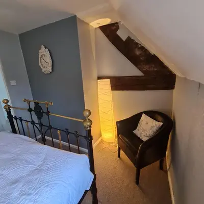 a bedroom with a bed and a chair at Abbey Cottage in Shrewsbury