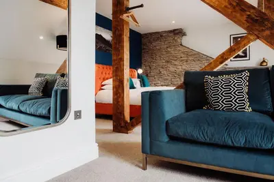 a bedroom with a blue chair and a bed at Devils Falls at the Luxury Hafod Hotel Aberystwyth in Devils Bridge