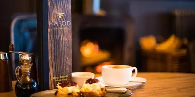 a table with a plate of food and a cup of coffee at Devils Falls at the Luxury Hafod Hotel Aberystwyth in Devils Bridge