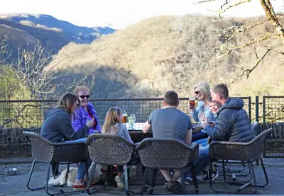 a group of people sitting at a table with mountains in the background at Devils Falls at the Luxury Hafod Hotel Aberystwyth in Devils Bridge