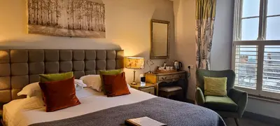 a bedroom with a bed and a chair and a window at The Castle Hotel in Bishops Castle