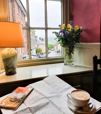 a table with a vase of flowers and a cup of coffee at The Castle Hotel in Bishops Castle
