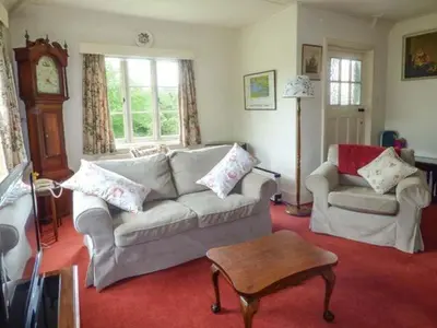 a living room with a couch and a table and a clock at Fiddlers Green in Bucknell