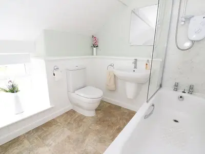 a white bathroom with a toilet and a tub and a sink at Penglanowen Fawr in Rhostie