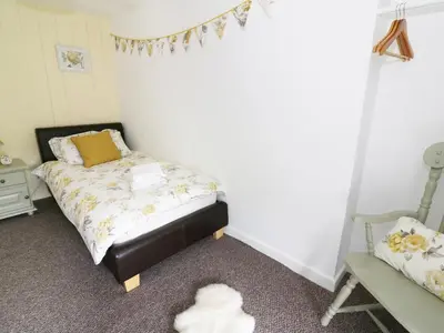 a small bedroom with a bed and a chair at Penglanowen Fawr in Rhostie