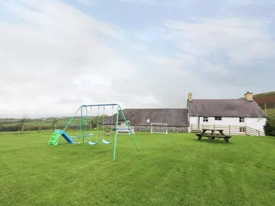 a playground with a slide and a bench in a yard at Penglanowen Fawr in Rhostie