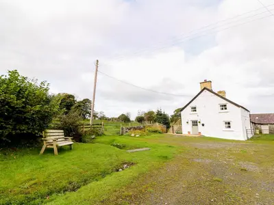 a white house with a picnic table and a bench at Penglanowen Fawr in Rhostie