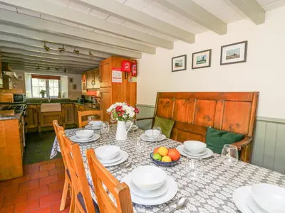a kitchen with a table with plates and bowls of fruit at Penuwch Fach in Llanfihangel-y-creuddyn