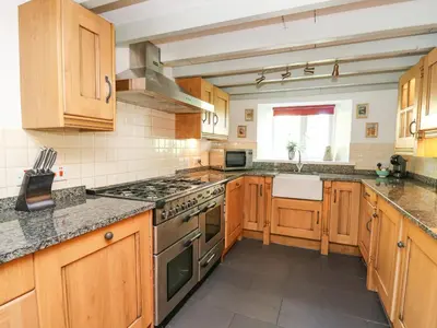 a kitchen with wooden cabinets and a stove top oven at Penuwch Fach in Llanfihangel-y-creuddyn