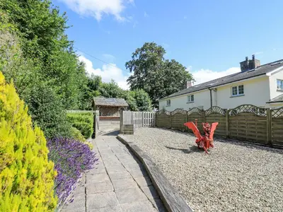 a garden with a red chair in a yard at Penuwch Fach in Llanfihangel-y-creuddyn