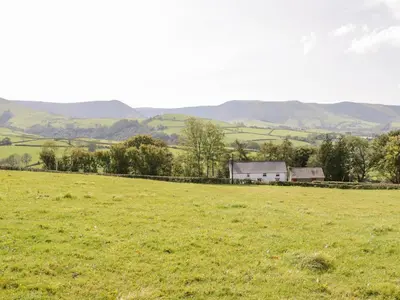 a field of green grass with a house in the distance at Bryndan in Machynlleth