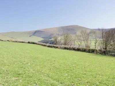 a green field with hills in the background at Bryndan in Machynlleth