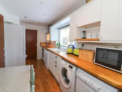 a kitchen with white cabinets and a washer and dryer at Dolau Meurig in Ystrad Meurig