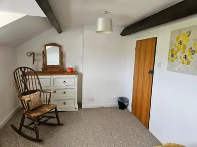 a room with a chair and a dresser and a mirror at Nant-Isa in Shelve