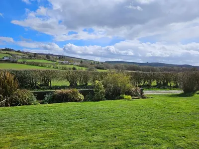 a field of green grass with trees and bushes at Nant-Isa in Shelve