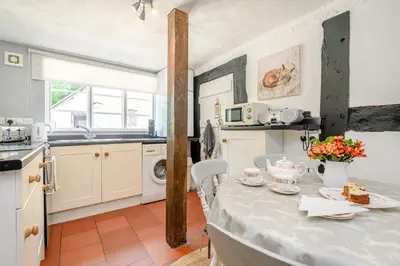 a kitchen with a table and a sink and a stove at Fern Hall Cottage in Upper Welson