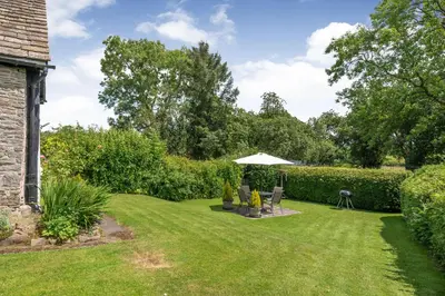 a garden with an umbrella and a lawn at Fern Hall Cottage in Upper Welson