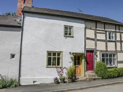 a white house with a red door on a street at Fern House in Craven Arms