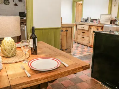 a wooden table with a plate and a bottle of wine at Fern House in Craven Arms