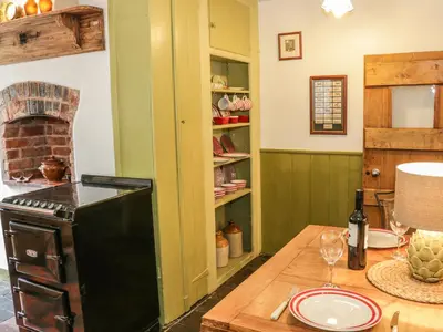 a kitchen with a stove and a table with wine glasses at Fern House in Craven Arms