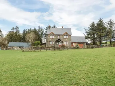 an old farm house with a field in the foreground at Blaen Henllan in Aberedw