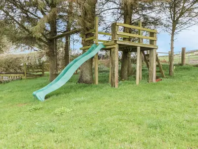 a blue slide in the grass next to a tree at Blaen Henllan in Aberedw