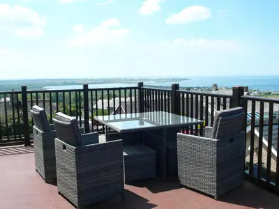 a table and chairs on a balcony with the ocean at Maesawel Studio in Harlech
