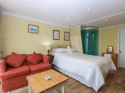 a bedroom with a bed and a red couch at Maesawel Studio in Harlech