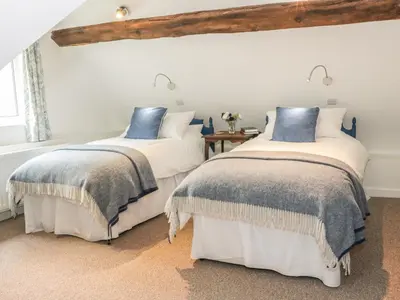 two beds in a white room with blue pillows at Lower Hodre in Bucknell