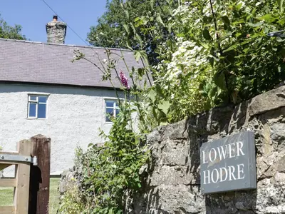 a sign on a stone wall in front of a house at Lower Hodre in Bucknell