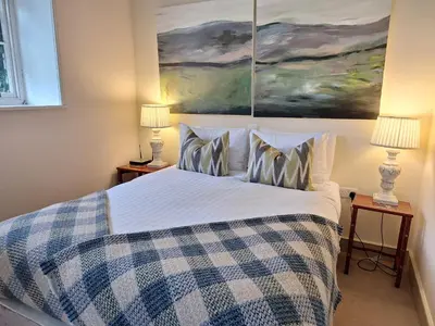 a bedroom with a bed with a blue and white checked blanket at Plas Nanteos Mansion in Aberystwyth