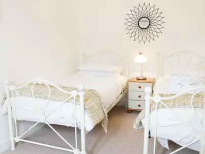 two white beds in a white bedroom with a mirror at Acorn Cottage 1 in Petton