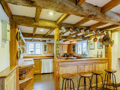 a kitchen with wooden cabinets and bar stools at Pant Dafydd Goch in Glyn-Ceiriog