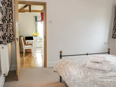 a bedroom with a bed and a dining room at Acorn Cottage 2 in Petton