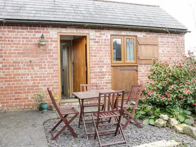 a table and chairs in front of a brick house at Acorn Cottage 2 in Petton