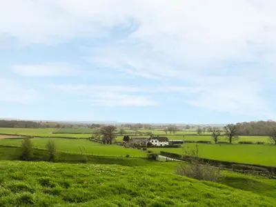a green field with a farm in the distance at Acorn Cottage 2 in Petton
