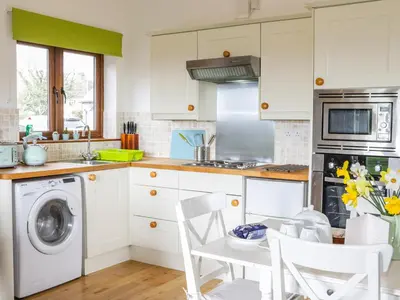 a kitchen with white cabinets and a washer and dryer at Acorn Cottage 2 in Petton