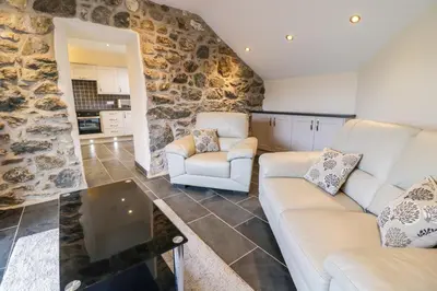 a living room with two couches and a stone wall at Bothi in Bala