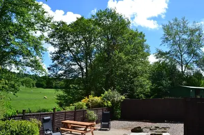 a picnic table in a backyard with a fence and a field at Arrowwood Self Catering (Wagtail and Nuthatch) in Kington