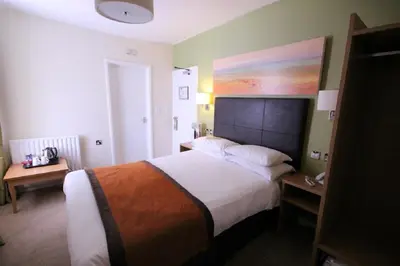 a bedroom with a large bed and a painting on the wall at The Wellington in Brecon